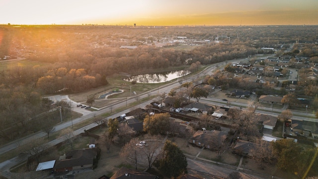 aerial view at dusk with a water view and a residential view