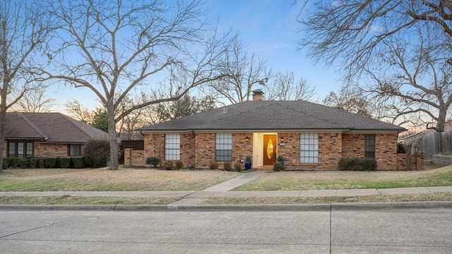 view of front facade featuring brick siding, a yard, and fence