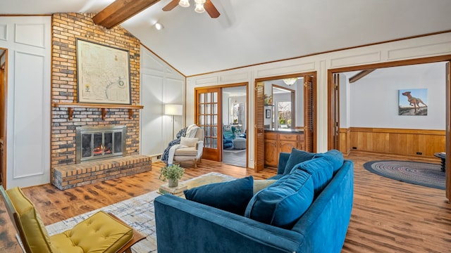 living room with vaulted ceiling with beams, light wood-type flooring, a fireplace, and a decorative wall