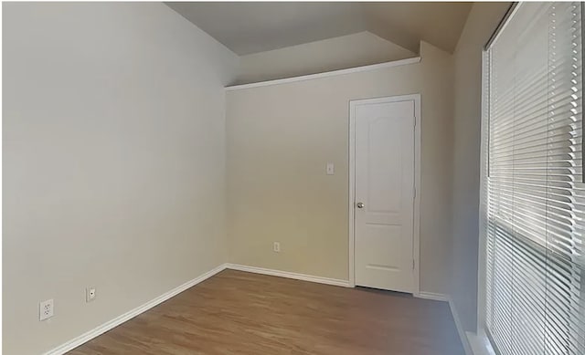 spare room featuring vaulted ceiling, wood finished floors, and baseboards