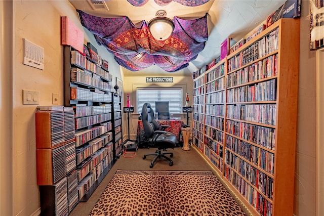 office area with wall of books, carpet, and visible vents