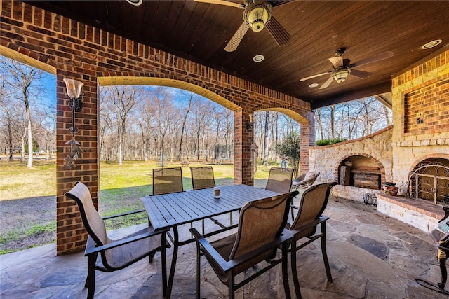 view of patio with an outdoor stone fireplace, ceiling fan, and outdoor dining area