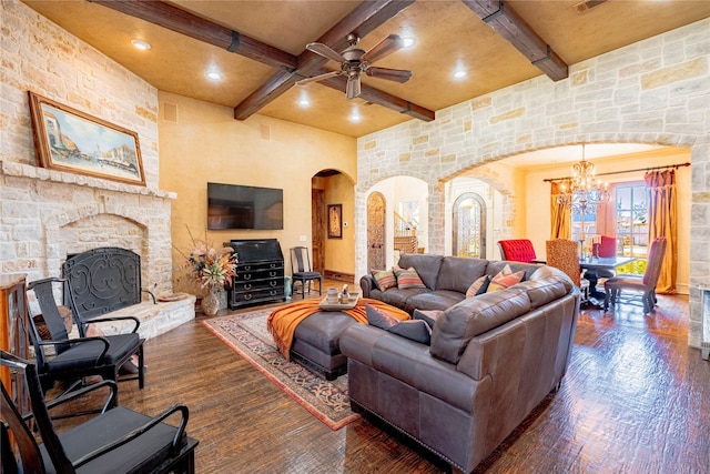 living room with dark wood-style floors, arched walkways, beamed ceiling, and a stone fireplace