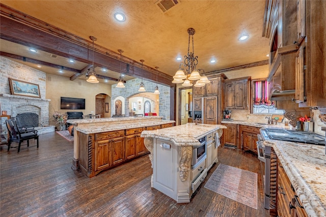 kitchen featuring visible vents, open floor plan, a center island, stainless steel stove, and pendant lighting