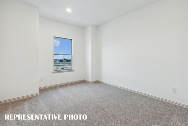 carpeted spare room featuring baseboards