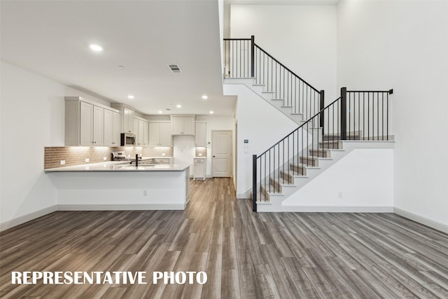 kitchen featuring a peninsula, visible vents, white cabinetry, light countertops, and stainless steel microwave