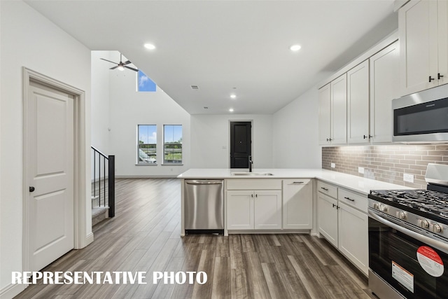 kitchen featuring stainless steel appliances, a peninsula, white cabinetry, open floor plan, and light countertops