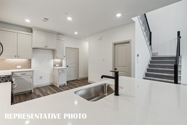 kitchen featuring backsplash, stainless steel range with gas stovetop, light countertops, and a sink