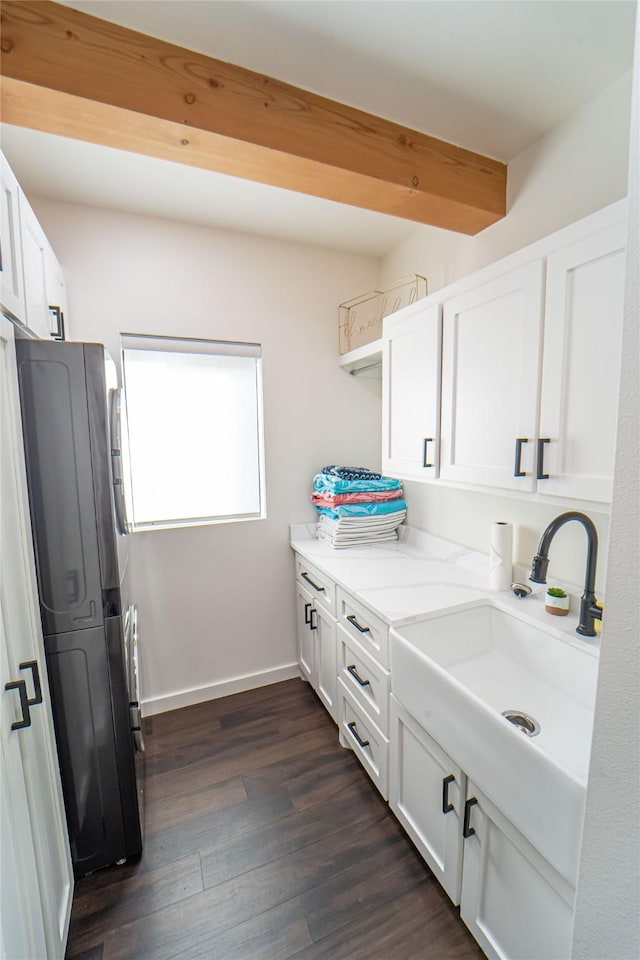 laundry area featuring washer / dryer, baseboards, dark wood finished floors, and a sink