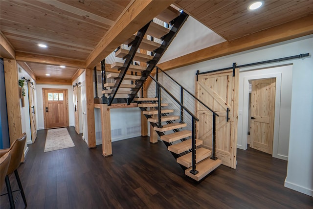 foyer entrance with a barn door, dark wood finished floors, and beam ceiling