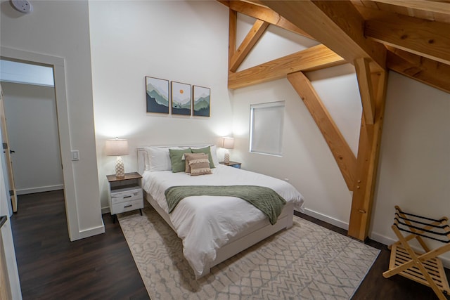 bedroom with wood finished floors, vaulted ceiling, and baseboards