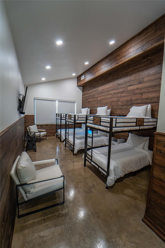 bedroom with wooden walls, wainscoting, recessed lighting, and finished concrete floors