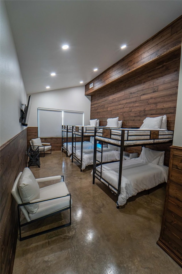 bedroom featuring recessed lighting, a wainscoted wall, finished concrete flooring, and wood walls