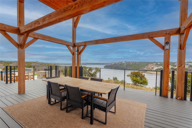 deck with outdoor dining area and a water view