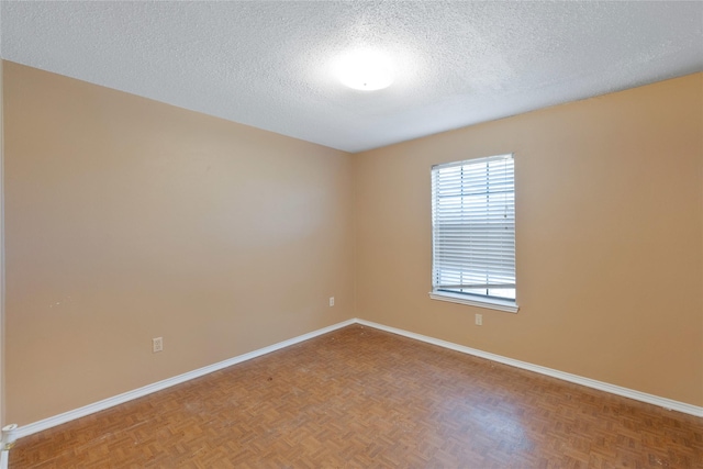 unfurnished room featuring a textured ceiling and baseboards