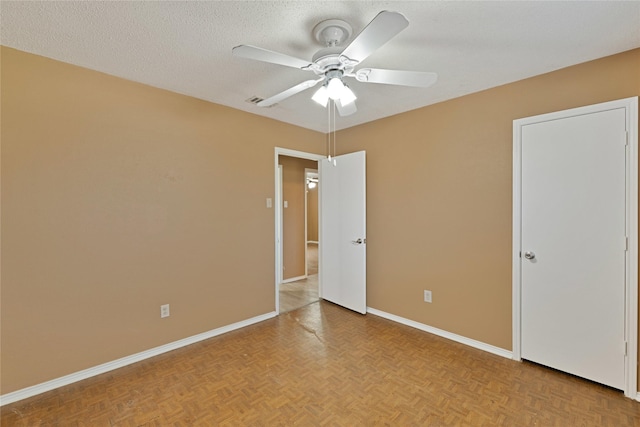 empty room with visible vents, ceiling fan, a textured ceiling, and baseboards