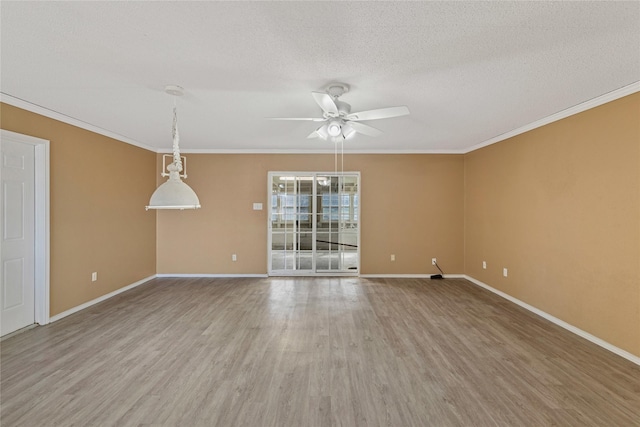 unfurnished room with crown molding, a textured ceiling, baseboards, and wood finished floors