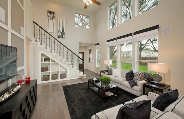 living area featuring ceiling fan, stairway, dark wood finished floors, and a wealth of natural light