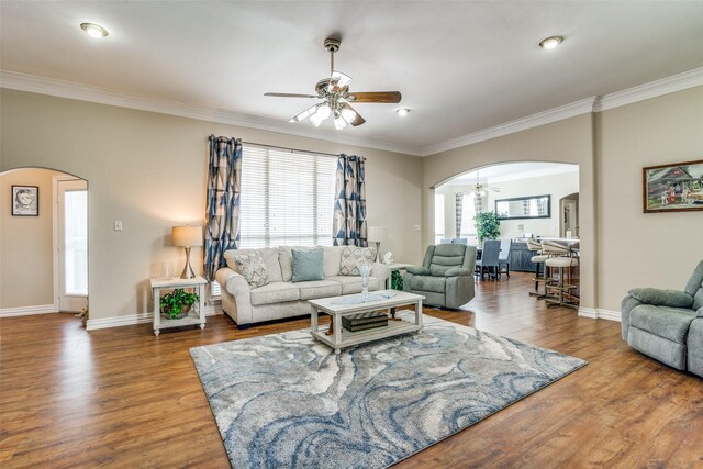 living area with ceiling fan, crown molding, arched walkways, and wood finished floors