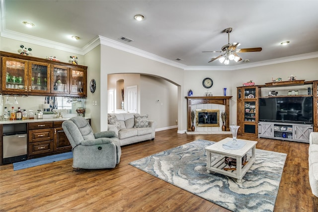 living room featuring a bar, a fireplace, arched walkways, and wood finished floors