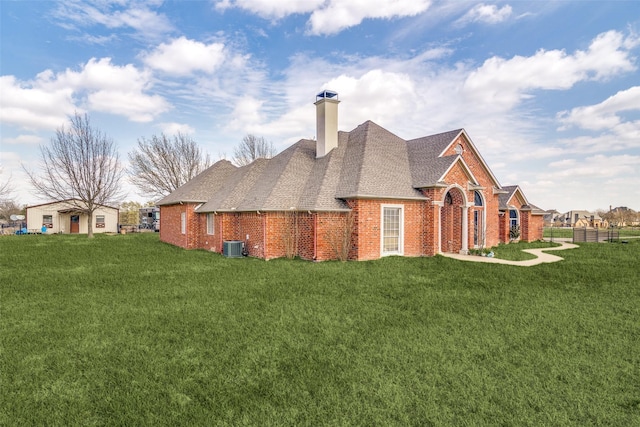 view of side of home with a shingled roof, brick siding, a yard, and a chimney