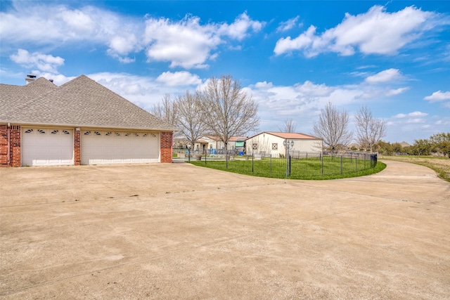 exterior space featuring a fenced front yard, brick siding, concrete driveway, roof with shingles, and a lawn