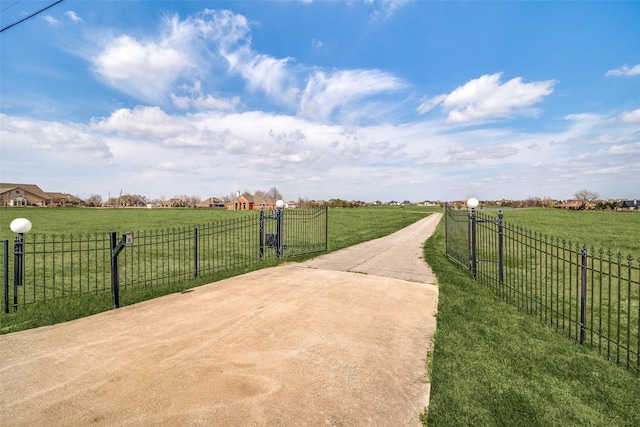 exterior space with a rural view, a lawn, fence, and a gate