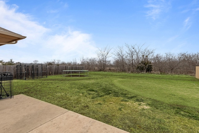 view of yard with a trampoline, fence, and a patio