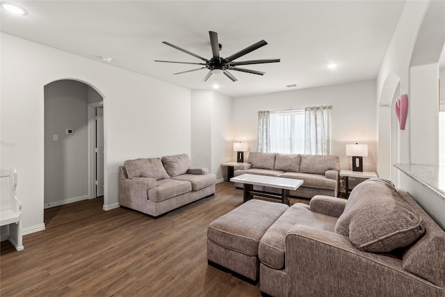 living room featuring dark wood-type flooring, arched walkways, baseboards, and recessed lighting