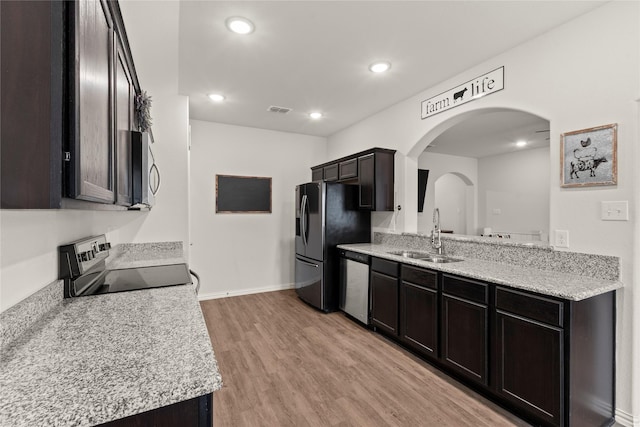 kitchen featuring arched walkways, visible vents, light wood-style flooring, appliances with stainless steel finishes, and a sink