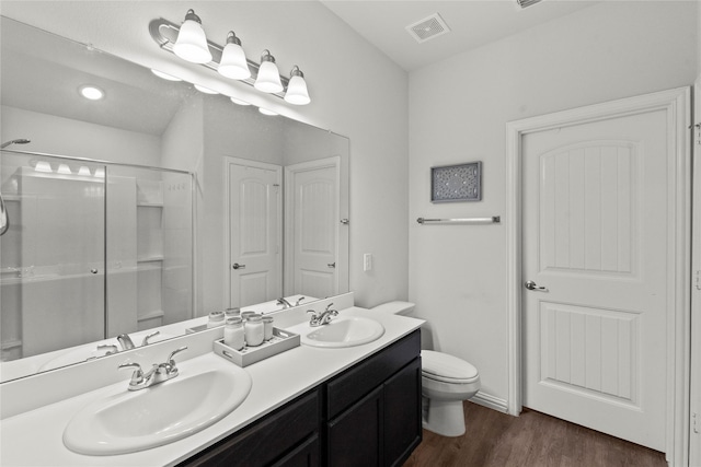 full bathroom with wood finished floors, a sink, visible vents, and a shower with door