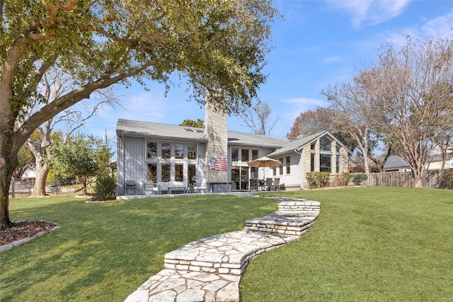 back of property featuring a yard, a patio, a chimney, and fence