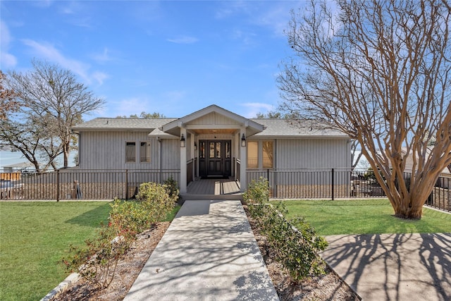 view of front of property with a fenced front yard, roof with shingles, and a front yard