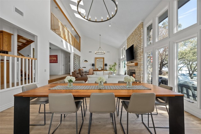 dining space with a chandelier, a fireplace, visible vents, and light wood-style floors