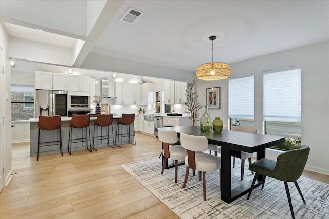 dining room featuring light wood finished floors, baseboards, and visible vents