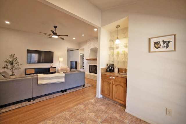 living area featuring a brick fireplace, recessed lighting, a ceiling fan, and light wood-type flooring