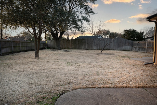 yard at dusk featuring a fenced backyard