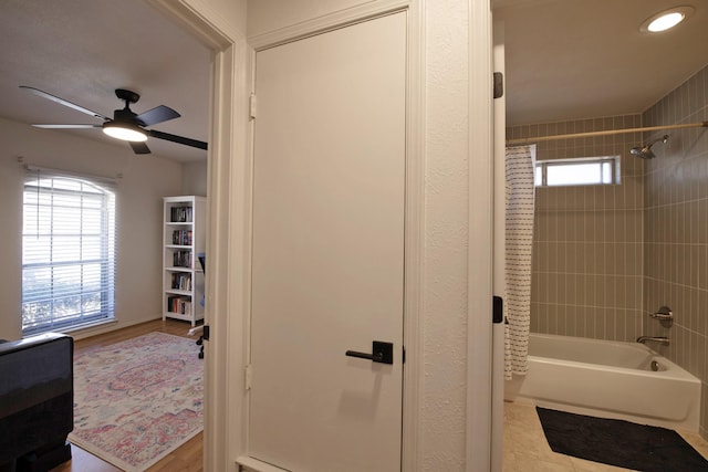 bathroom with shower / tub combination, a ceiling fan, and wood finished floors