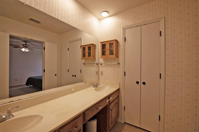 bathroom featuring a sink, visible vents, double vanity, and wallpapered walls