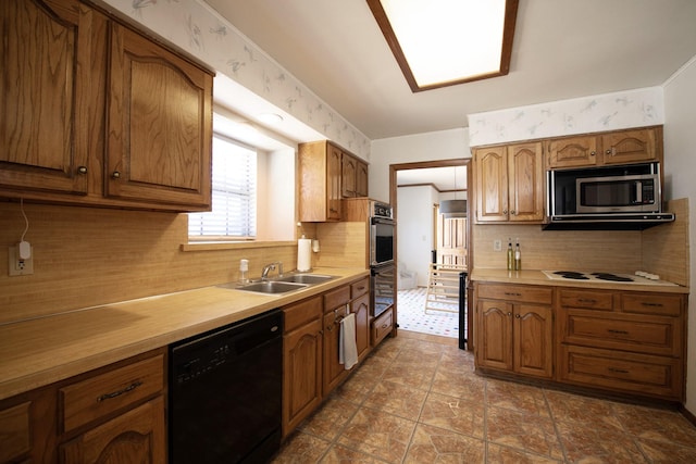kitchen with dishwasher, a sink, light countertops, brown cabinets, and stainless steel microwave