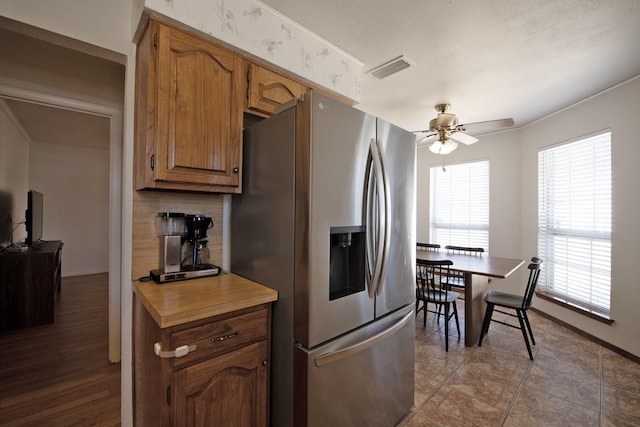 kitchen featuring visible vents, a ceiling fan, stainless steel fridge, light countertops, and decorative backsplash