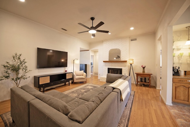 living area with crown molding, visible vents, ceiling fan, and light wood-style flooring
