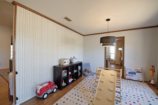 rec room featuring visible vents, ornamental molding, and wood finished floors