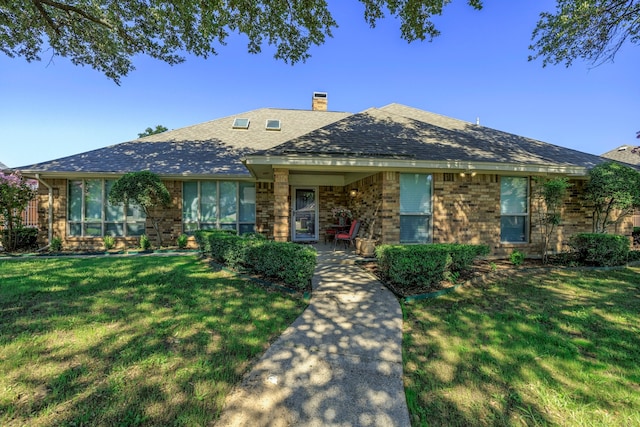 single story home featuring a front yard, brick siding, a chimney, and roof with shingles