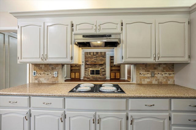 kitchen featuring white cabinets, under cabinet range hood, black electric stovetop, and light countertops