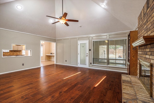 unfurnished living room with ceiling fan, high vaulted ceiling, a brick fireplace, and wood finished floors