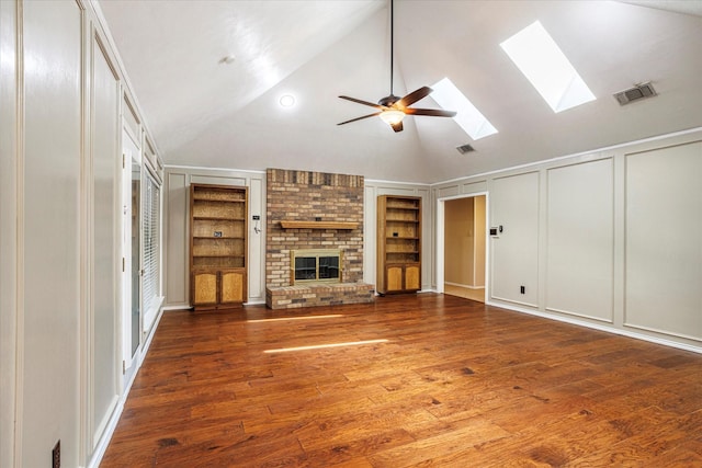 unfurnished living room featuring built in shelves, a brick fireplace, visible vents, and a decorative wall