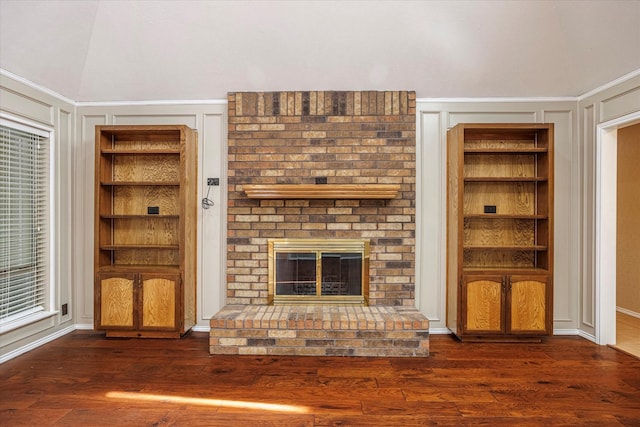 unfurnished living room with dark wood-type flooring, a brick fireplace, and a decorative wall