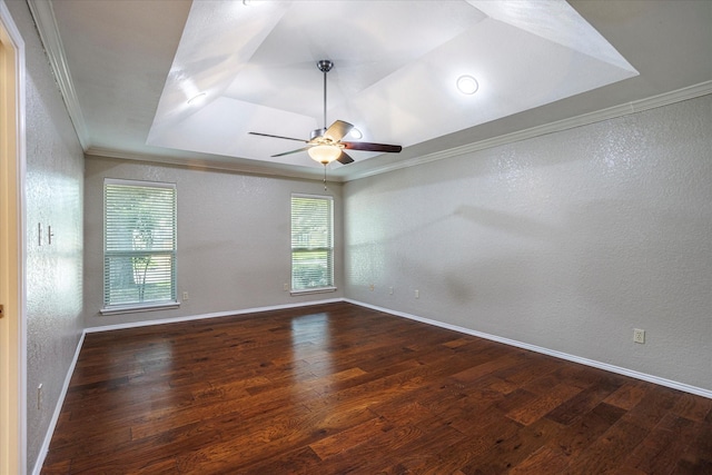 spare room with dark wood-style floors, a raised ceiling, a textured wall, ornamental molding, and baseboards