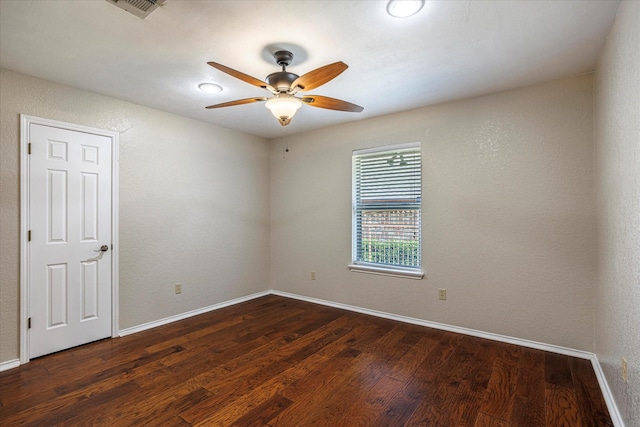 unfurnished room featuring a ceiling fan, a textured wall, dark wood finished floors, and baseboards